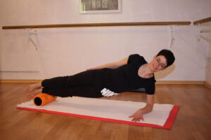 Pilates intensiv Trainerin Mandy im Seitstütz, die Füße auf einer Faszienrolle
